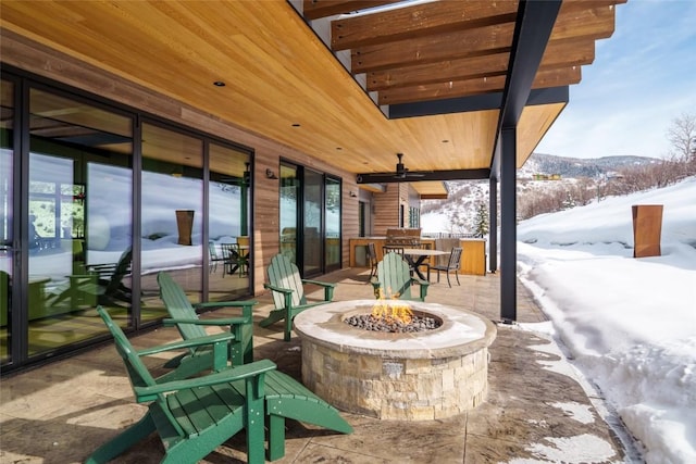 33200 Meadow Creek Dr, Steamboat Springs, CO 80487 - snow covered patio featuring a fire pit, a ceiling fan, a mountain view, and a patio area
