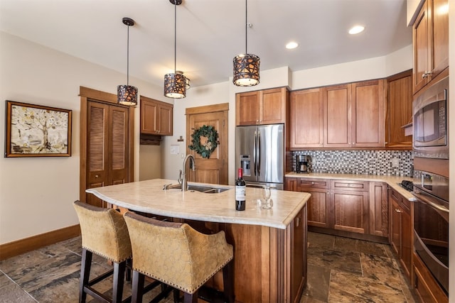 kitchen featuring a sink, backsplash, stone finish flooring, stainless steel fridge with ice dispenser, and an island with sink