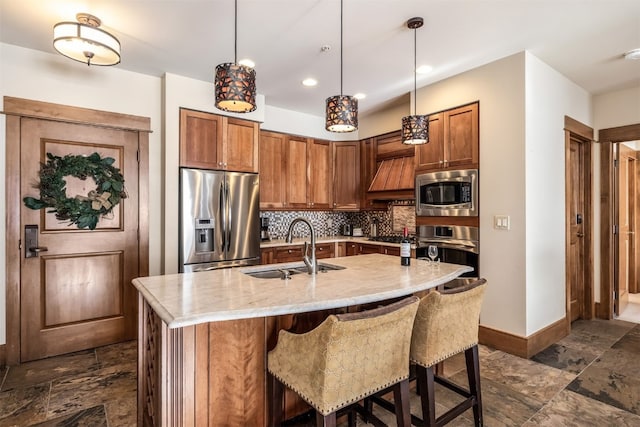 kitchen featuring stainless steel appliances, a sink, baseboards, backsplash, and stone finish flooring