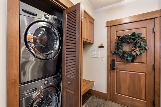 washroom featuring stacked washer / drying machine, baseboards, and laundry area