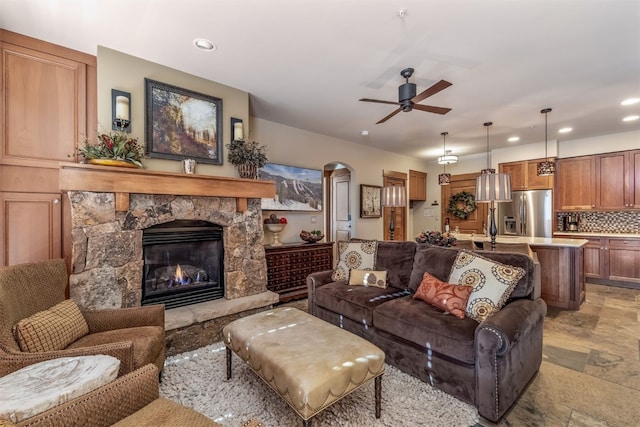 living room with a fireplace, a ceiling fan, stone finish floor, and recessed lighting