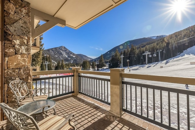 snow covered back of property featuring a mountain view