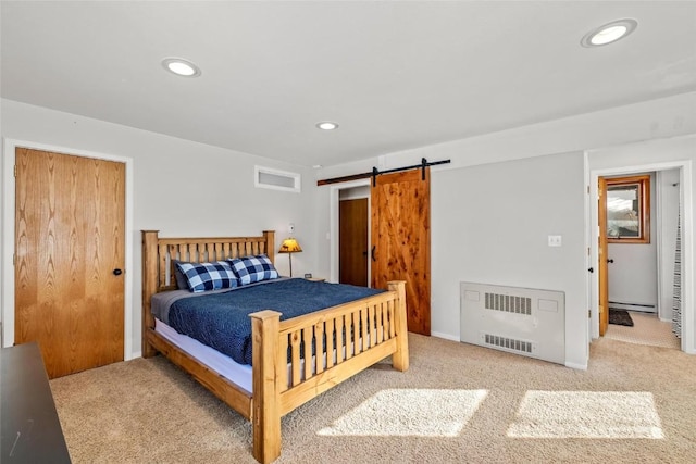 bedroom with a baseboard heating unit, radiator, a barn door, and carpet flooring