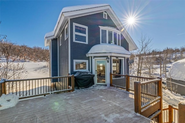 snow covered rear of property featuring a wooden deck