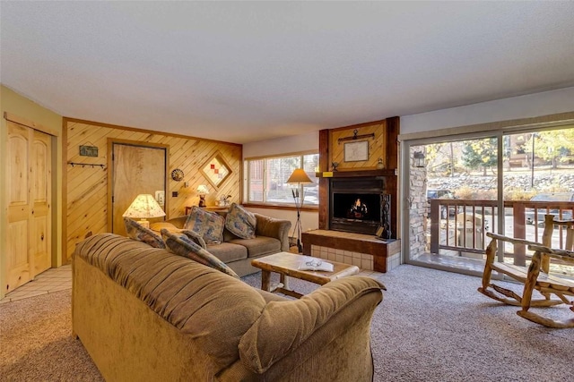 living room with light carpet, a tile fireplace, and wooden walls