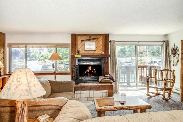 living area with a baseboard radiator, carpet floors, a textured ceiling, and a lit fireplace