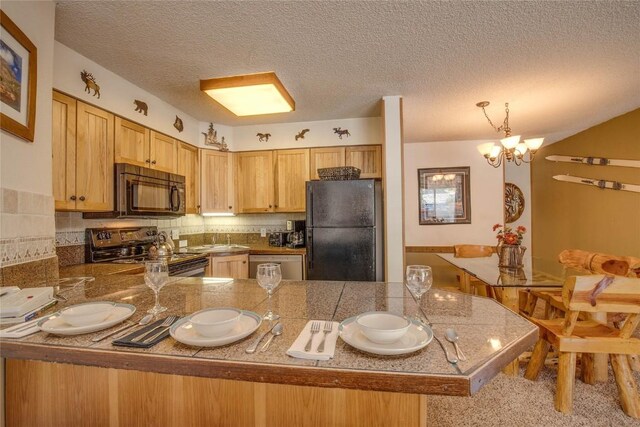 kitchen with tile counters, an inviting chandelier, black appliances, a peninsula, and a textured ceiling