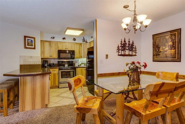 kitchen featuring black appliances, a peninsula, tasteful backsplash, a breakfast bar area, and a notable chandelier