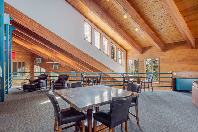 dining room featuring wood walls, beamed ceiling, high vaulted ceiling, wood ceiling, and carpet