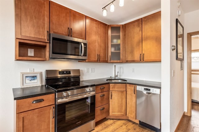 kitchen featuring a sink, dark countertops, stainless steel appliances, and light wood finished floors