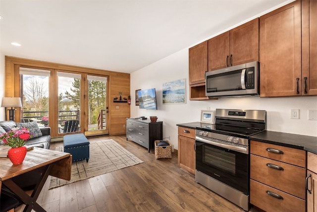 kitchen with dark countertops, dark wood-type flooring, a baseboard heating unit, brown cabinets, and stainless steel appliances