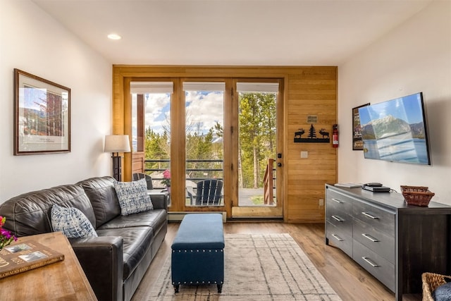 living area featuring recessed lighting, light wood-style flooring, a baseboard heating unit, and wooden walls