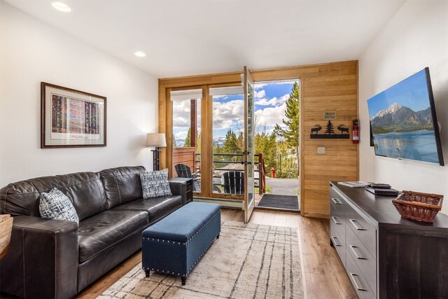 living area with light wood-style floors, recessed lighting, and wooden walls