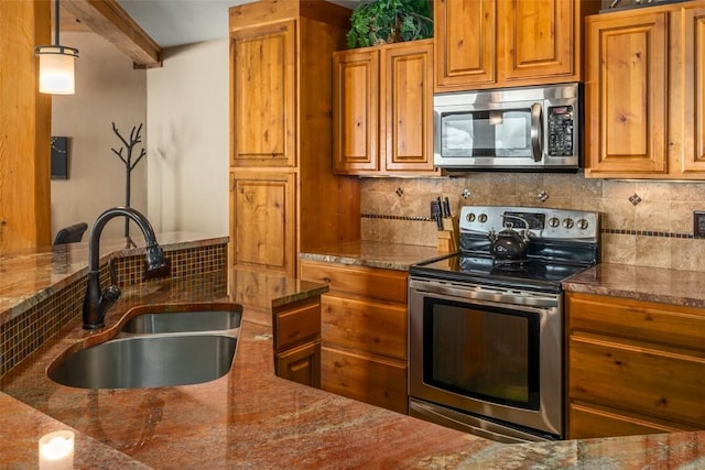 2700 Village Dr Unit B102, Steamboat Springs, CO 80487 - kitchen featuring appliances with stainless steel finishes, a sink, brown cabinetry, decorative backsplash, and dark stone counters