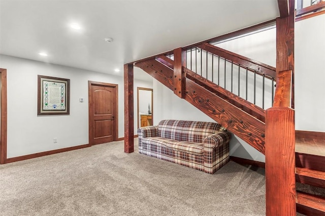 living area featuring baseboards, carpet floors, and stairs