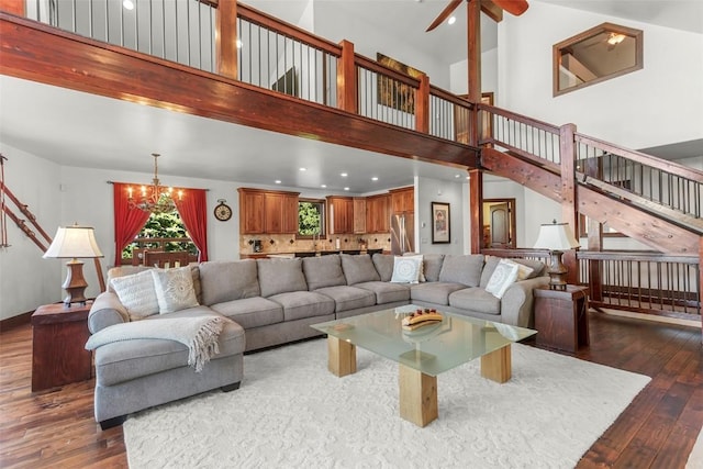 living room with recessed lighting, a towering ceiling, hardwood / wood-style flooring, stairs, and ceiling fan with notable chandelier