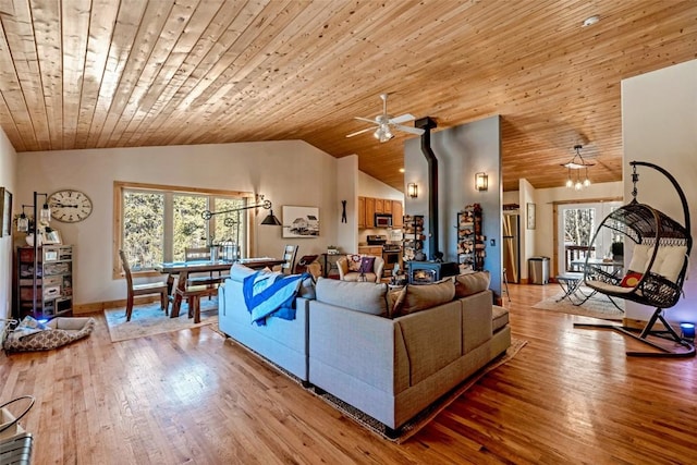 living area featuring vaulted ceiling, a wood stove, a wealth of natural light, and wood ceiling