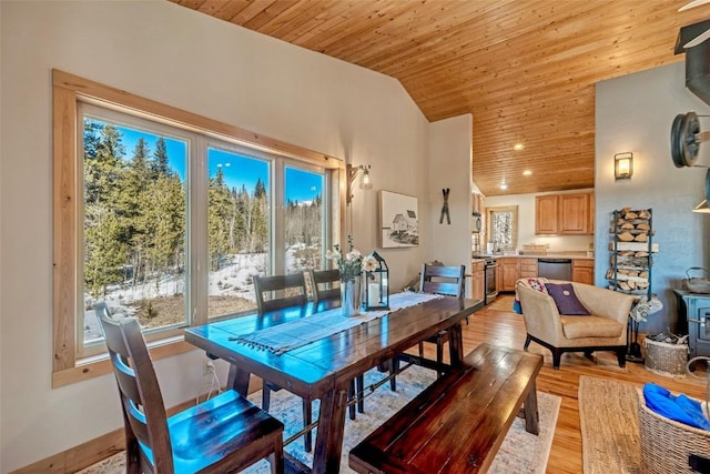 dining room with wood ceiling, vaulted ceiling, a wood stove, and light wood-type flooring