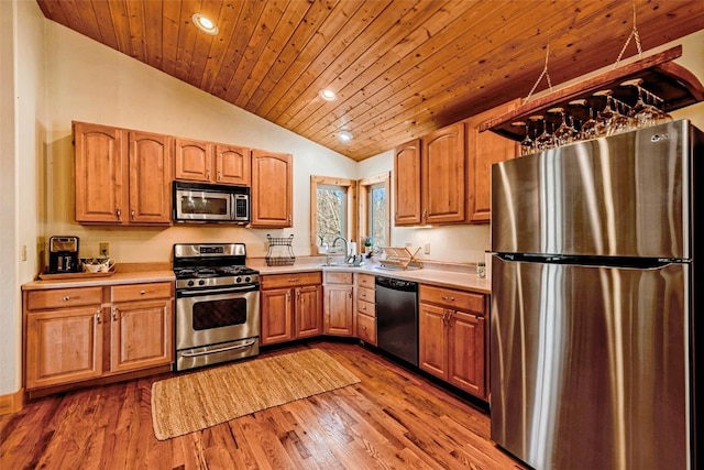kitchen featuring stainless steel appliances, a sink, recessed lighting, lofted ceiling, and light countertops