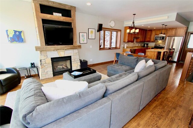115 Beeler Pl Unit 1, Copper Mountain, CO 80443 - living room with light wood finished floors, baseboards, recessed lighting, a chandelier, and a stone fireplace