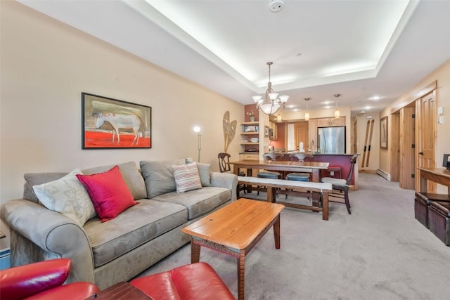 living room featuring a chandelier, a tray ceiling, and light colored carpet