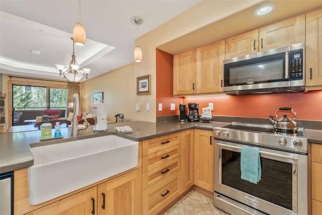 kitchen with appliances with stainless steel finishes, light brown cabinets, a sink, a chandelier, and a peninsula