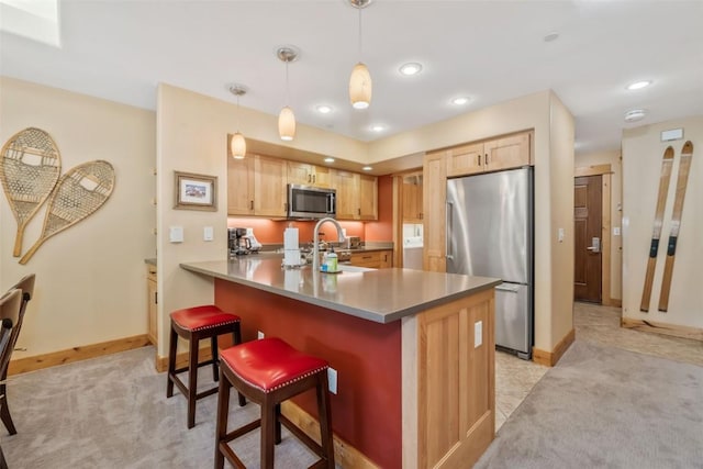 kitchen with stainless steel appliances, light carpet, a peninsula, a kitchen breakfast bar, and baseboards