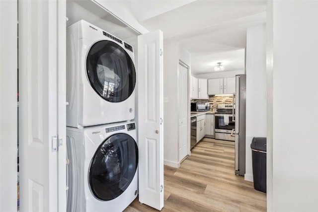 laundry room with stacked washer and dryer, laundry area, and light wood-style flooring