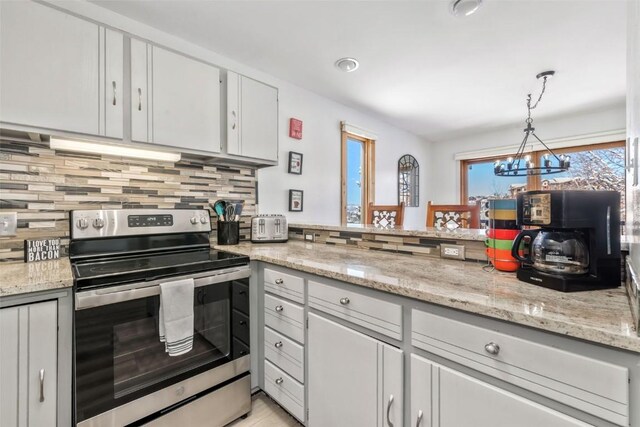 kitchen featuring tasteful backsplash, stainless steel electric stove, pendant lighting, white cabinetry, and a notable chandelier