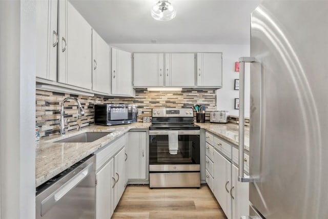 kitchen with tasteful backsplash, appliances with stainless steel finishes, white cabinetry, and a sink