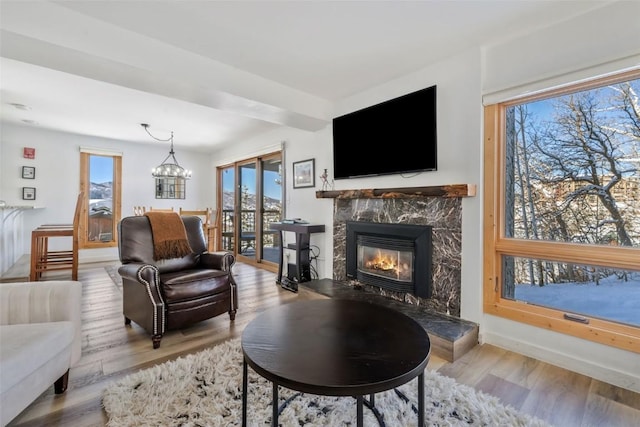 living room featuring a fireplace, a chandelier, wood finished floors, and baseboards