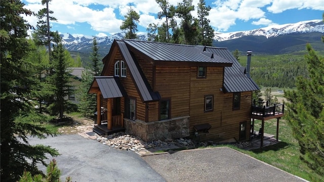 511 Fairview Blvd, Breckenridge, CO 80424 - view of property exterior with a standing seam roof, a metal roof, stone siding, a deck with mountain view, and asphalt driveway