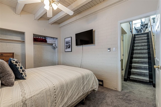 bedroom with beam ceiling, ceiling fan, wooden ceiling, brick wall, and carpet floors