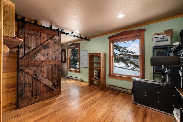 26395 County Road 33a, Steamboat Springs, CO 80487 - living room with a baseboard radiator, a textured ceiling, light wood-style flooring, a barn door, and recessed lighting