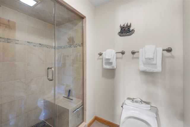 full bathroom with a shower stall, toilet, and baseboards