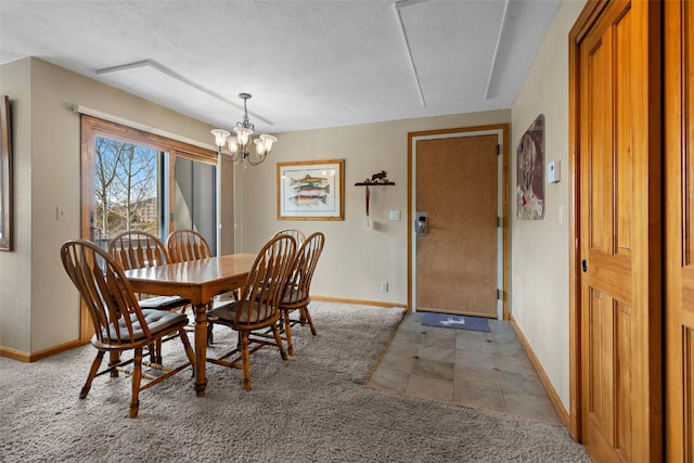 dining space with a chandelier, a textured ceiling, and baseboards