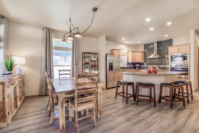 dining room featuring baseboards, light wood finished floors, and recessed lighting