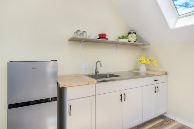 kitchen with open shelves, wood counters, light wood-style floors, white cabinetry, and freestanding refrigerator