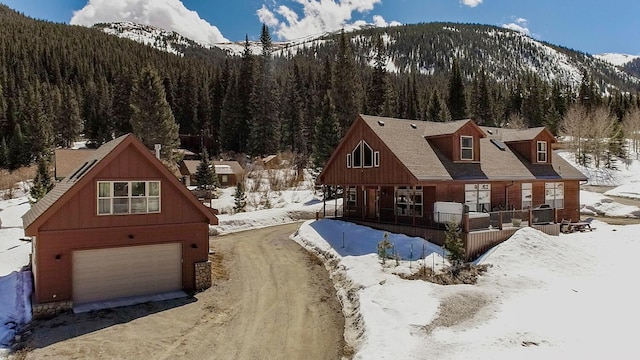 view of front of home featuring an attached garage, driveway, covered porch, a view of trees, and a mountain view