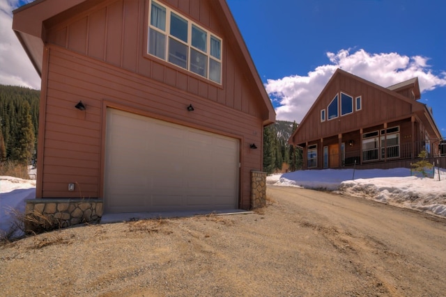exterior space with board and batten siding, an attached garage, and driveway
