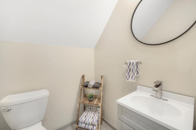 half bath with vaulted ceiling, toilet, and vanity