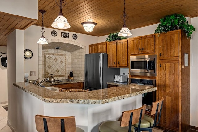 kitchen with kitchen peninsula, a kitchen bar, wood ceiling, stainless steel appliances, and pendant lighting