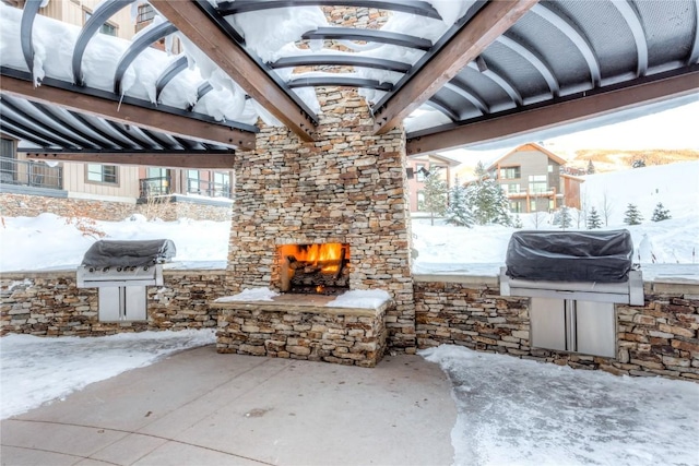 snow covered patio with an outdoor stone fireplace and area for grilling