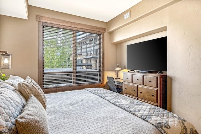 bedroom featuring a textured wall and visible vents