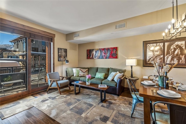 living room featuring wood finished floors, visible vents, and a notable chandelier