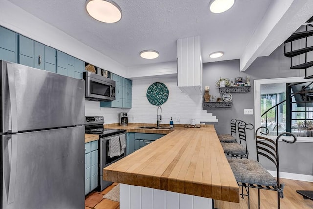 136 Lance Ln Unit 2, Breckenridge, CO 80424 - kitchen with appliances with stainless steel finishes, blue cabinets, wooden counters, and a textured ceiling