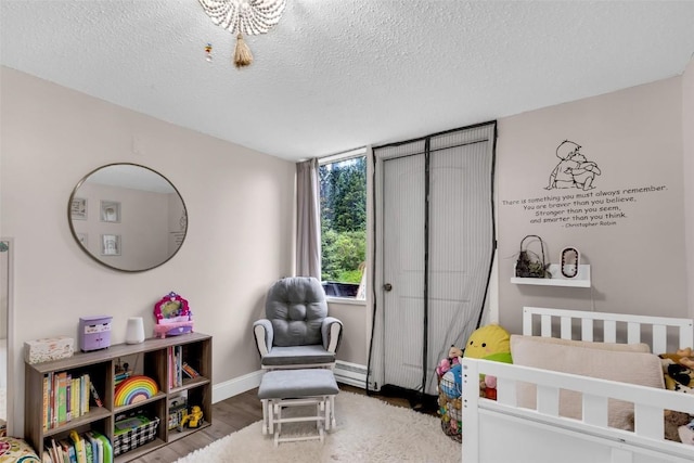 136 Lance Ln Unit 2, Breckenridge, CO 80424 - bedroom featuring a baseboard heating unit, a textured ceiling, wood finished floors, and a nursery area