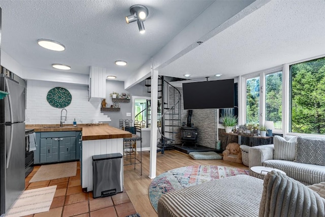 136 Lance Ln Unit 2, Breckenridge, CO 80424 - kitchen with wood counters, open floor plan, a textured ceiling, a wood stove, and electric stove