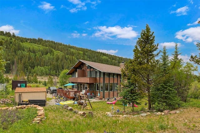 136 Lance Ln Unit 2, Breckenridge, CO 80424 - back of house featuring a wooded view, a sunroom, a chimney, a storage shed, and a wooden deck