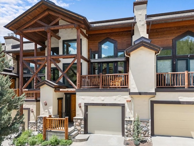 2743 Timber Ct Unit 3, Steamboat Springs, CO 80487 - rear view of property featuring an attached garage, a chimney, and stucco siding